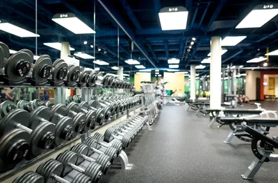 Racks of dumbbells and benches on the gym floor
