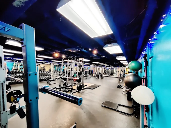 A wide view of the gym floor at ONE Boulder Fitness, with squat racks, benches and free weights