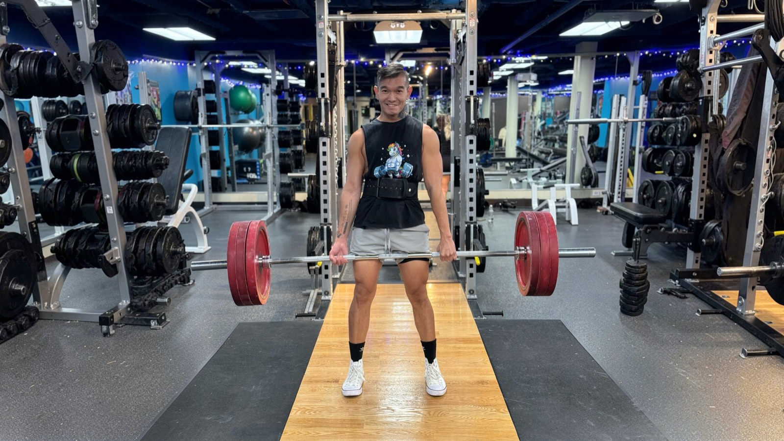 A member deadlifting a loaded barbell on the gym floor at ONE Boulder Fitness