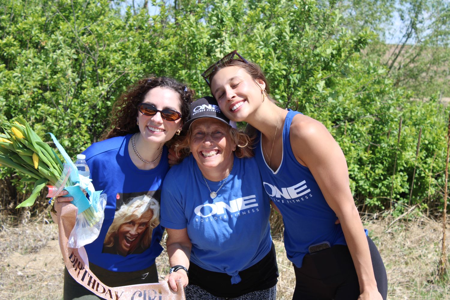 Three ONE Boulder Fitness members squeezed together laughing