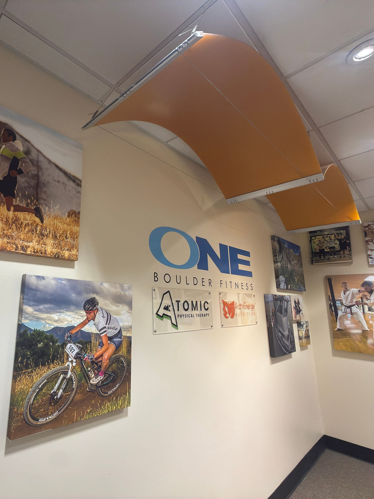 The lobby wall with the ONE Boulder Fitness, Atomic Physical Therapy and ActivEnergy Nutrition signs together