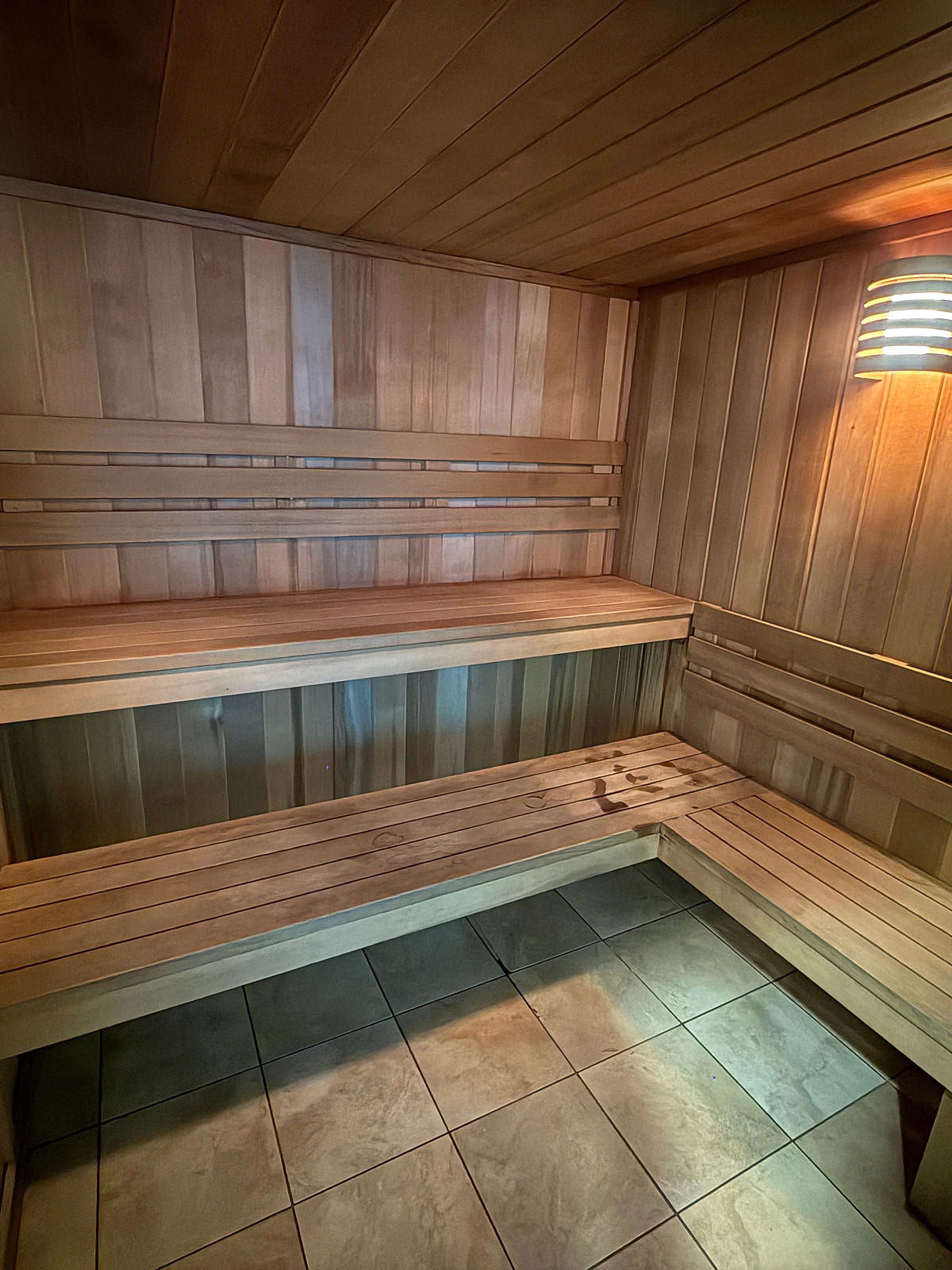 The cedar sauna at ONE Boulder Fitness glowing under its wall lamp