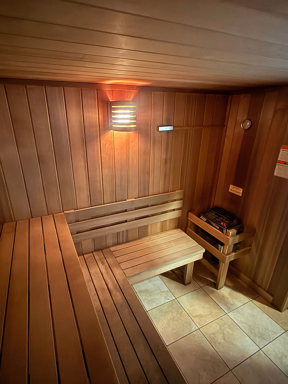 Inside the cedar sauna at ONE Boulder Fitness — tiered benches, warm wall lamp and the heater