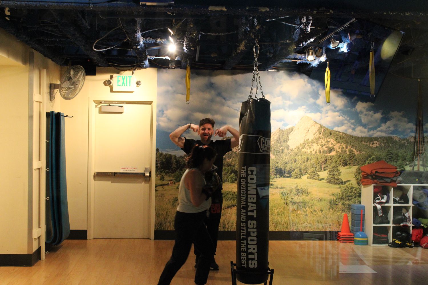 Two members on the heavy bag in the studio, one of them flexing